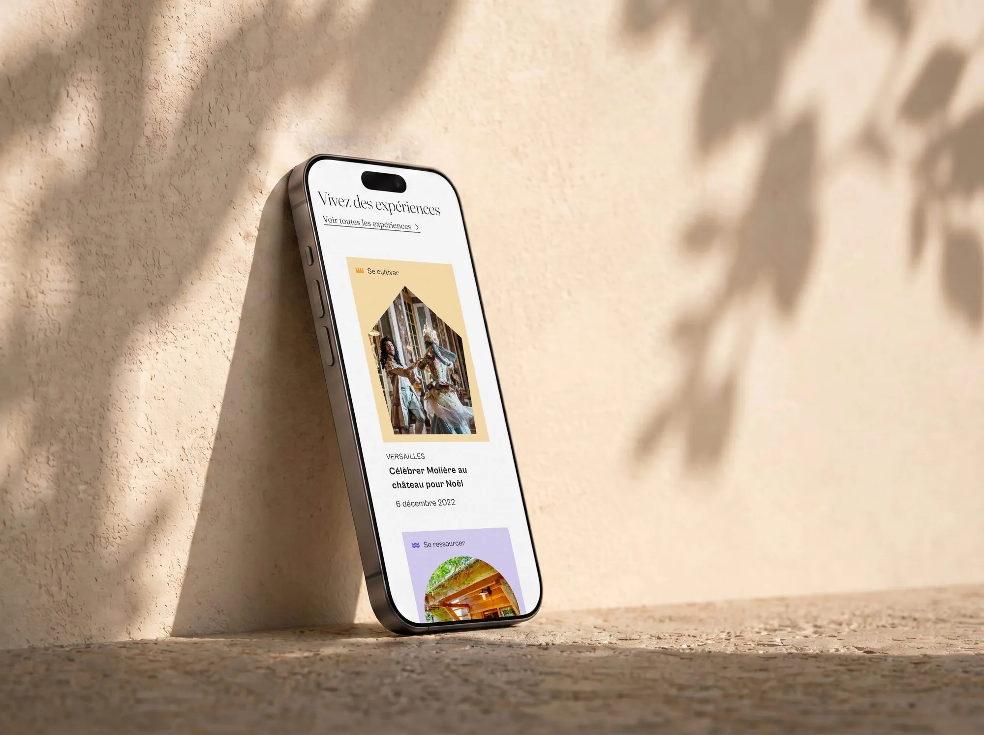 Rubrique Vivez des expériences sur smartphone posé contre un mur ensoleillé